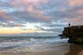 Man stands on cliffside overlooking ocean waves