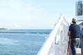 A man stands on the deck of a cruise ship and looks at the shore on a Sunny day Royalty Free Stock Photo