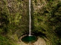 A man stands in front of the massive 100m high waterfall Levada do Caldeirao Verde on Madeira Island