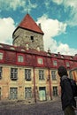 A man stands with his back and looks at an old beautiful building with red tiles in the old city of Tallinn. Royalty Free Stock Photo