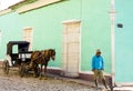 Man stands with horse and cart taxi on street in Trinidad, Cuba. Royalty Free Stock Photo