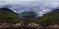 Man stands by lake in red jacket in cloudy weather. Spherical panorama 360vr Royalty Free Stock Photo