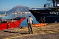 Man stands beside a large vessel in a body of water in Patras, Greece