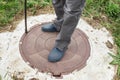 A man stands on the lid of a sewer well. Maintenance of sewerage and water systems