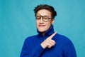 man stands on a light blue background in a blue zip-up sweater with black-rimmed glasses turned upside down on his face Royalty Free Stock Photo