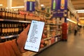 A man stands with a list on a smartphone to buy groceries and goods in supermarket, store, wholesale warehouse. Shopping in shop