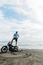 Man stands on a motorcycle. Ocean beach Bali. back wheel of a motorcycle in sand. male person looking for inspiration