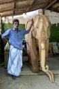 A man stands next to a carved elephant statue. Royalty Free Stock Photo