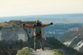 Man stands with open arms on the edge of a cliff in Crimean mountains