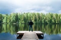 Man stands on the pier of a beautiful lake. Young man enjoying life, Man welcomes the beauty of nature, he is happy