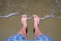 Man stands in sea barefeet on sandy beach. Royalty Free Stock Photo