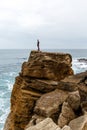 Man stands on a sea cliff, dark stormy sea on background