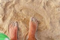 Man stands in the sea and looks at his foot in the sand and water close