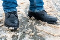 A man stands on the sidewalk in snow and mud. Black shoes and blue jeans close-up on the background of dirty snow. Ice on the road Royalty Free Stock Photo