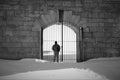 Man stands in silhouette at gated stone entranceway