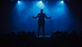 A man stands on a stage in front of a crowd of people. He is holding a microphone and he is a singer or a speaker. Royalty Free Stock Photo