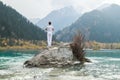 A man stands on a stone in the center of a mountain lake and practices yoga. Pose Vrikshasana Royalty Free Stock Photo