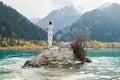 A man stands on a stone in the center of a mountain lake and practices yoga. Pose Vrikshasana Royalty Free Stock Photo