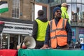 Man stands beside a table at a rally event in an orange high viz vest with a loud mega phone Royalty Free Stock Photo