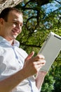 Man stands with tablet near the tree