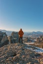 A man stands on top of a rocky mountains and enjoys the beautiful view of Meteora Monastery in Greece