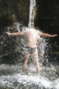 A man stands under a stream of water under a waterfall, summer, hot Royalty Free Stock Photo