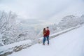 A man stands in warm clothes in winter and embraces a woman warming her with his warmth in cold weather