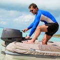 Man starting a motor boat at the beach. He smiling Royalty Free Stock Photo