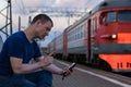 A man with vitiligo at a railway station talking on a smartphone and threatening with his finger