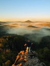 Man stay on the rocky peak and within daybreak watch over the misty and foggy morning valley. Beautiful autumn morning. Royalty Free Stock Photo