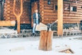 Man staying in the country house porch. Wooden stump with axe on snowy yard unfocused with heavy snowflakes . Winter countryside h