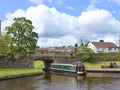 Man steering canal narrowboat under bridge