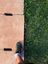 Man step up on right foot in green sneaker. cement drain grate and green grass with abstract background Royalty Free Stock Photo
