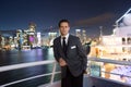 Man steward on ship board at night in miami, usa. Macho in suit jacket on city skyline. Water transport, transportation. Travellin Royalty Free Stock Photo