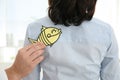Man sticking paper fish to colleague`s back, closeup. April fool`s day