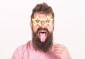 Man with stickout tongue, closed eyes and beard wearing paper star shaped glasses, fun concept. Hipster with crazy look Royalty Free Stock Photo