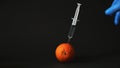 A man sticks a syringe of carcinogens into an orange