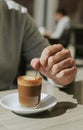 Man stirring his machiatto with a spoon