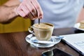 Man is stirring spoon of sugar in cup of cappuccino coffee Royalty Free Stock Photo