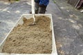 The man stirs sand and cement in a large trough to make the solution