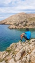 Stara Baska - A young man sitting on a rock with Stara Baska Beach view