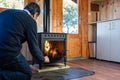 Man stoking the fire in a rustic cast iron fireplace to heat the house in winter Royalty Free Stock Photo