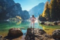 Man on the stone on the coast of Braies lake at sunrise