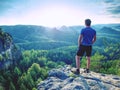 Man on stone observing the landscape. Lonely young sportsman stands on the mountain and looks into the far distance