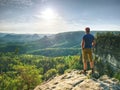 Man on stone observing the landscape. Lonely young sportsman stands on the mountain and looks into the far distance