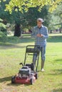 Man stood by lawnmower using smartphone Royalty Free Stock Photo