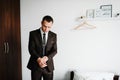 The man is straightens a jacket at home. The groom in a shirt, tie is standing in room. Close up. Handsome man model in formal Royalty Free Stock Photo