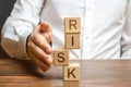 A man straightens a segment in an unstable tower of cubes labeled Risk. Risk management, cost assessment, and business Royalty Free Stock Photo