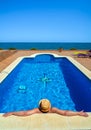 Man in a straw hat in the water with his arms outstretched leaning on the edge of a luxury resort pool relaxing looking in wonder Royalty Free Stock Photo