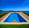 Man in a straw hat in the water with his arms outstretched leaning on the edge of a luxury resort pool relaxing looking in wonder Royalty Free Stock Photo